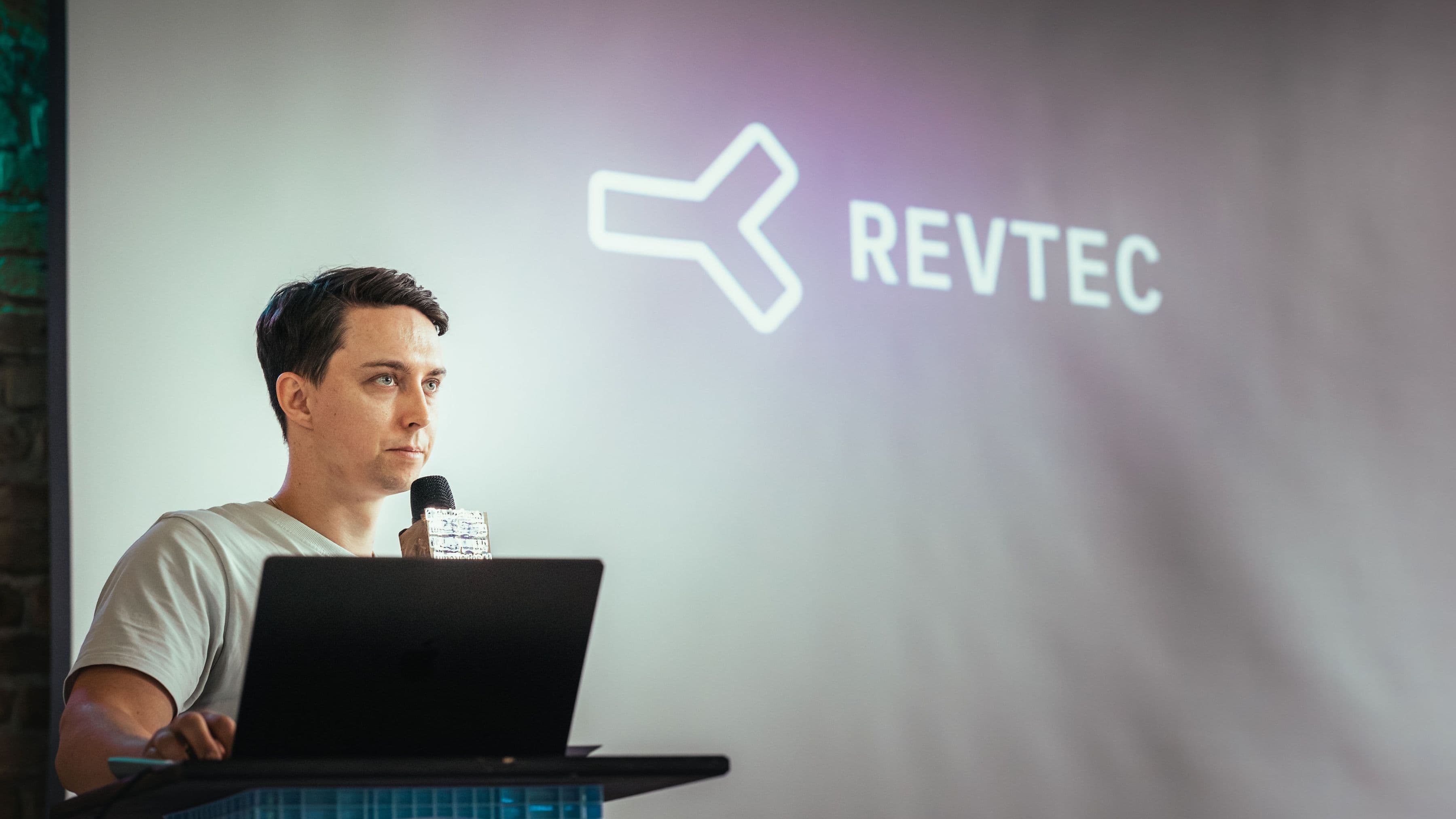 Presenting RevTec on stage with a laptop and microphone