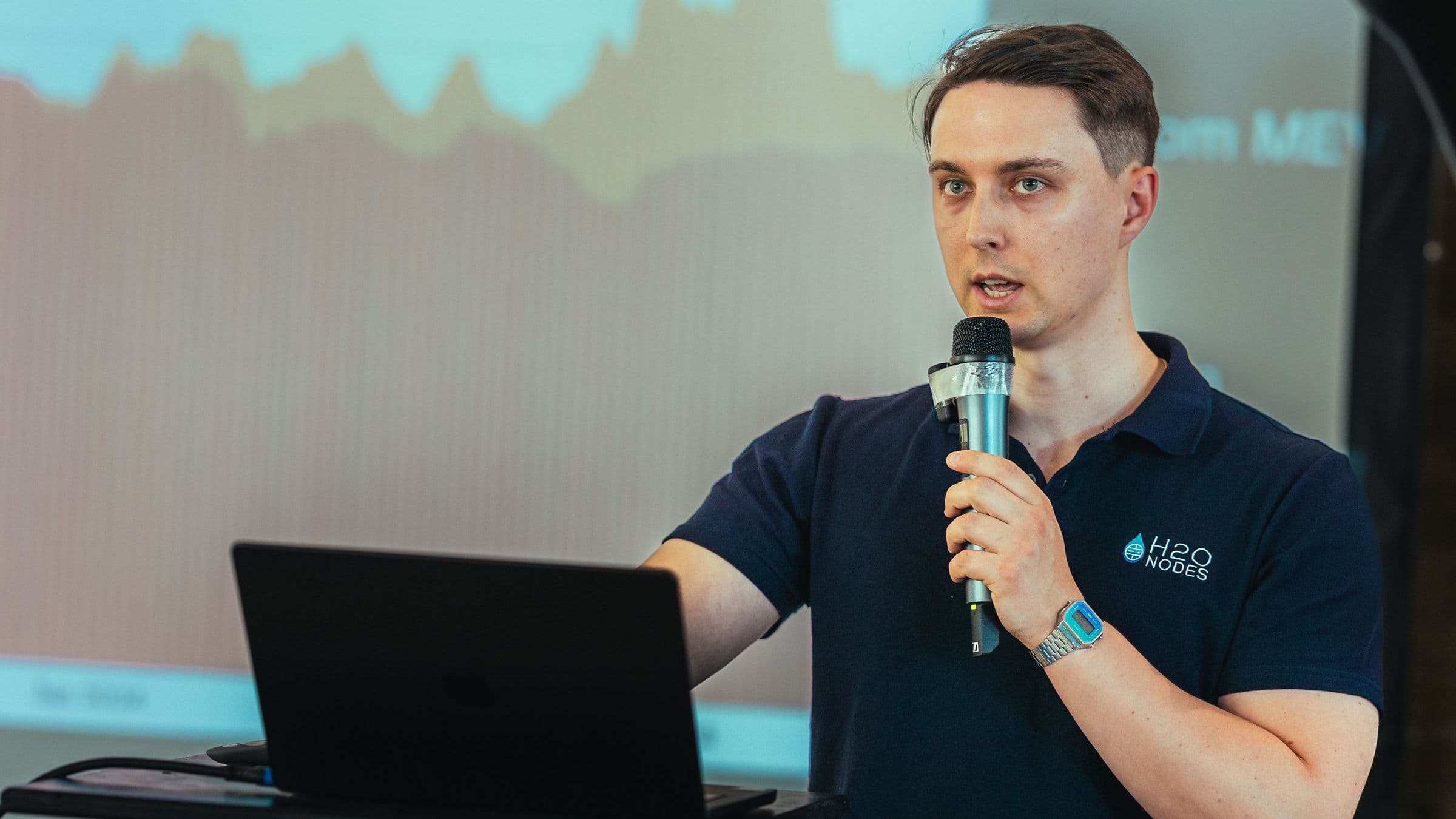 Presenting with an H2O Nodes polo and microphone